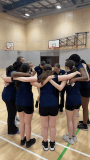 girls in the gymnasium doing a huddle stamping feet