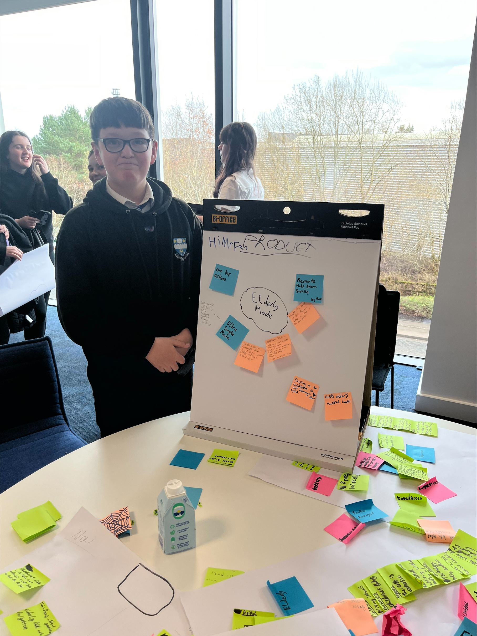 boy stands next to board with notes on it