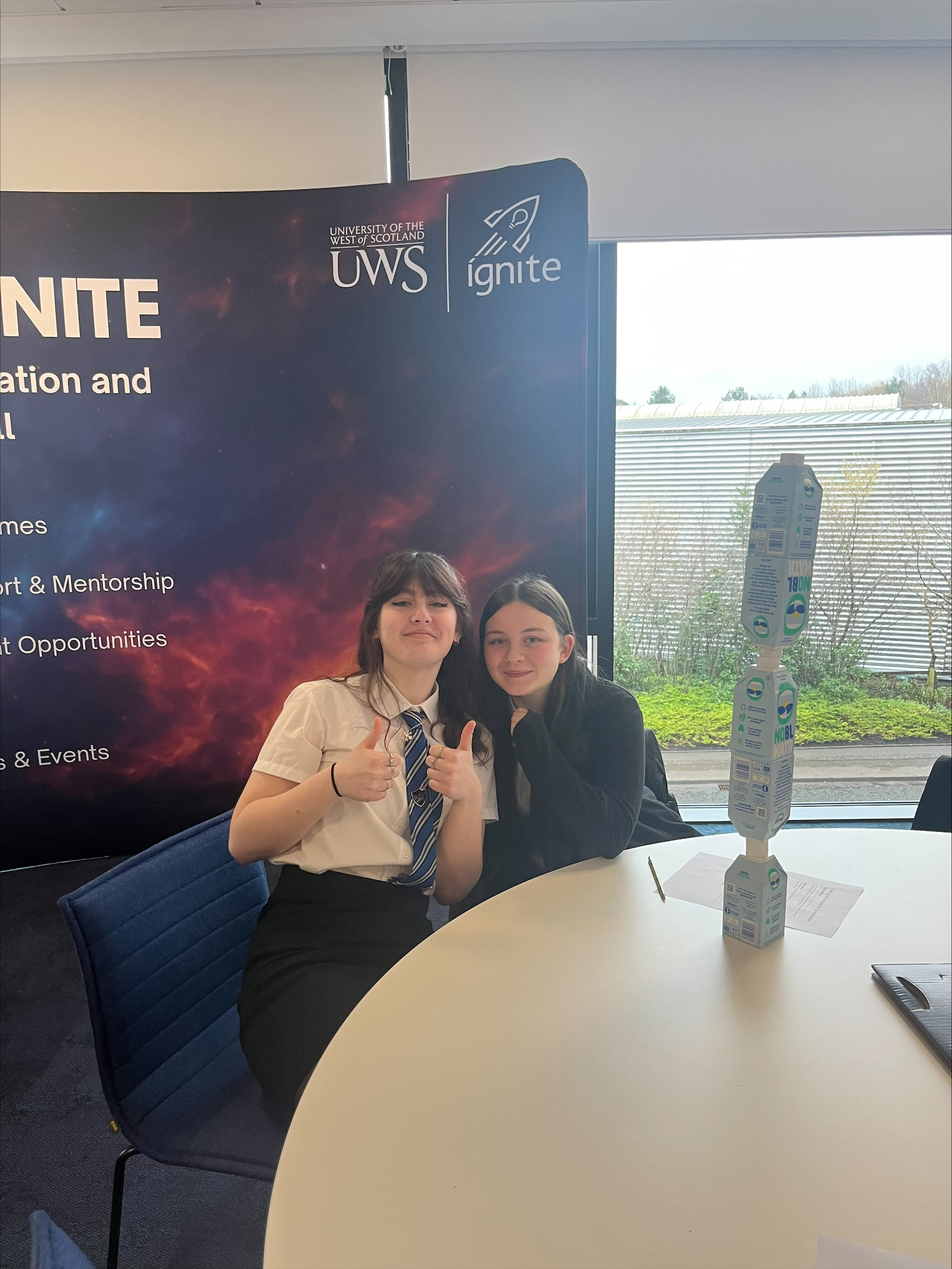 two girls smile together and give a thumbs up