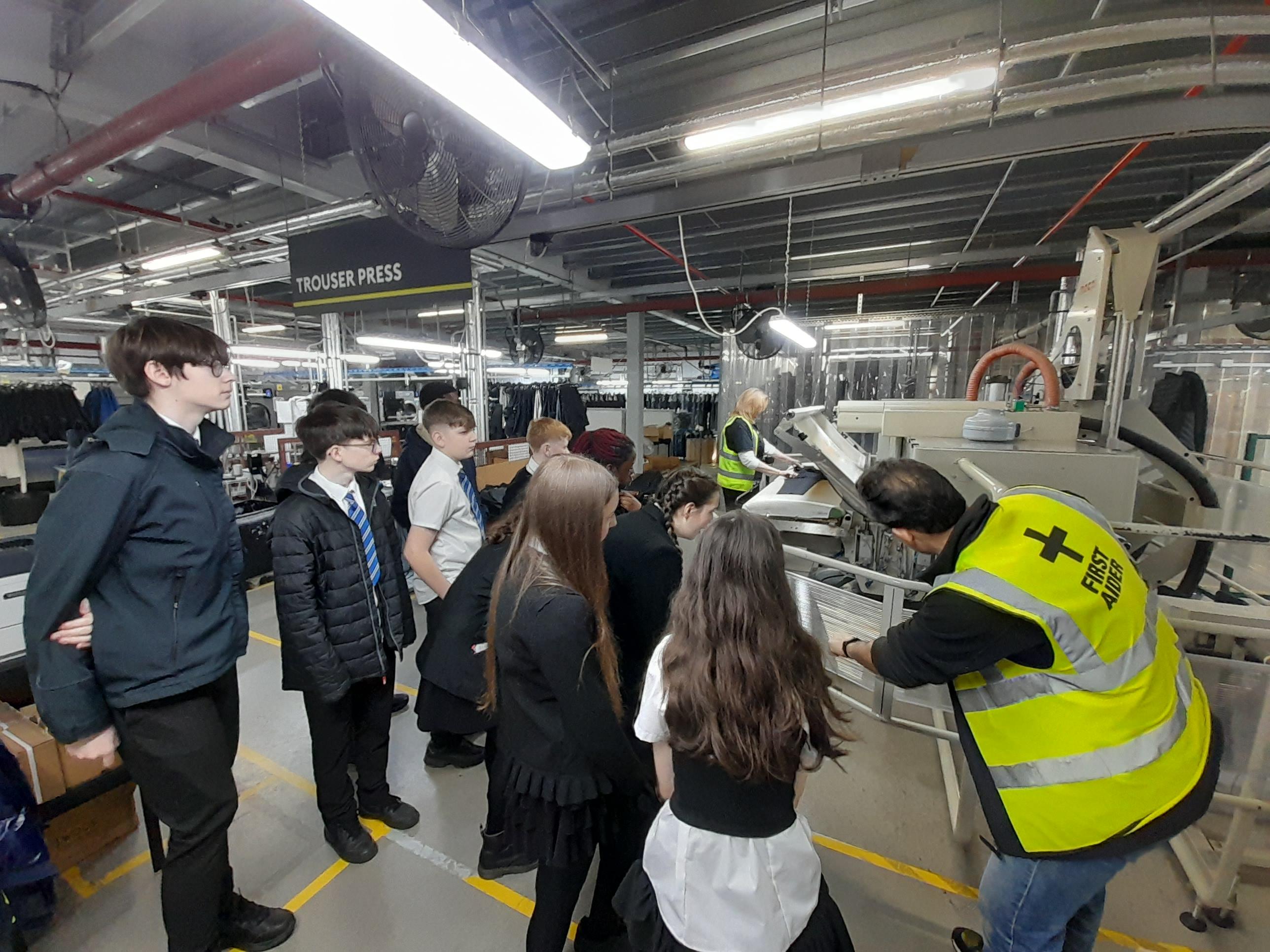 pupils inside the clothing manufacturers listening to a man giving a demostration