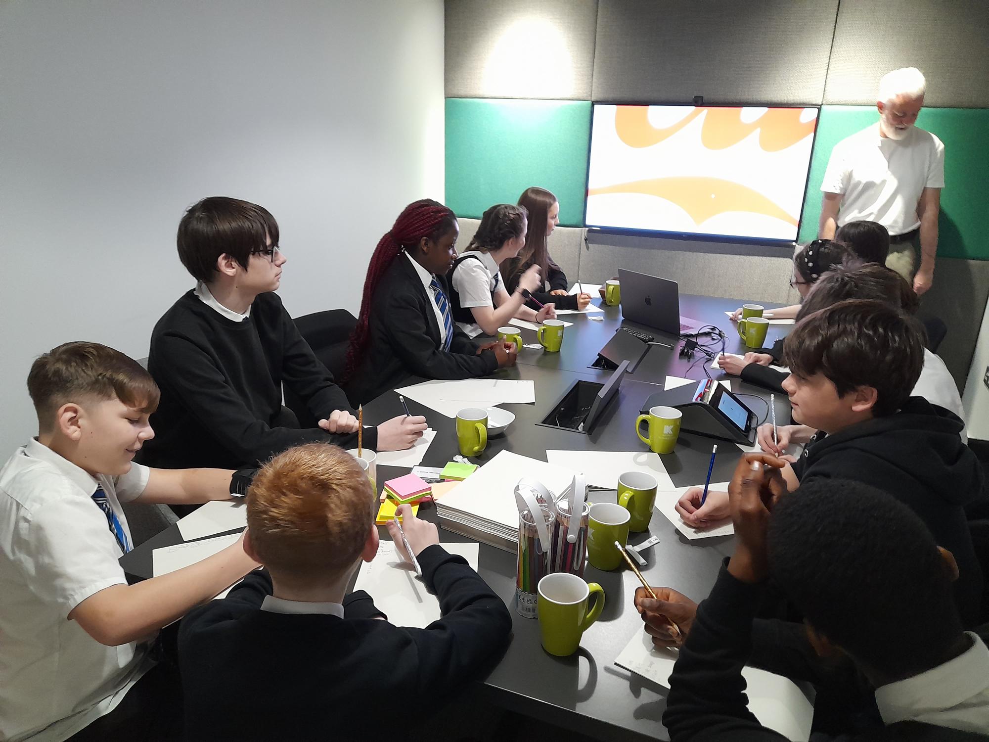 pupils sat around a large table taking notes on notepads