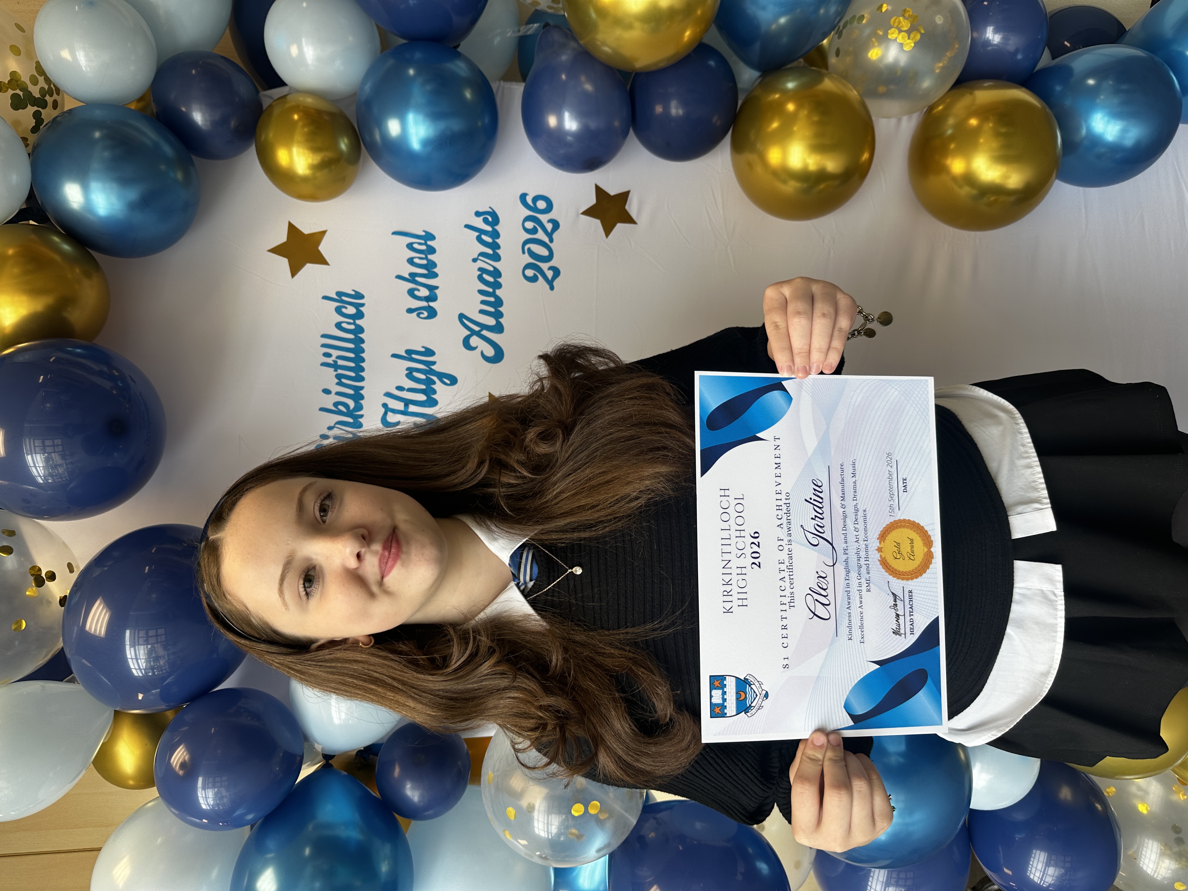 pupil smiling while holding a certificate of achievement
