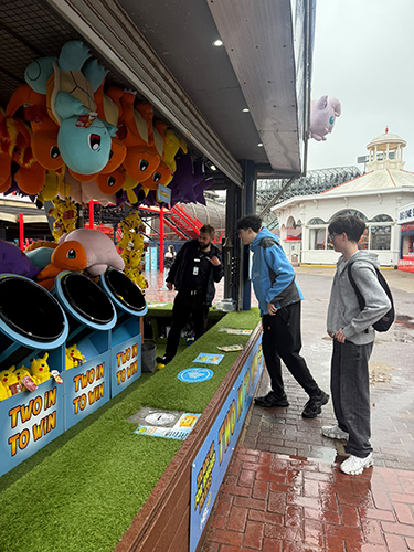 Boys playing at a stall where they need to throw a ball in a bucket to win