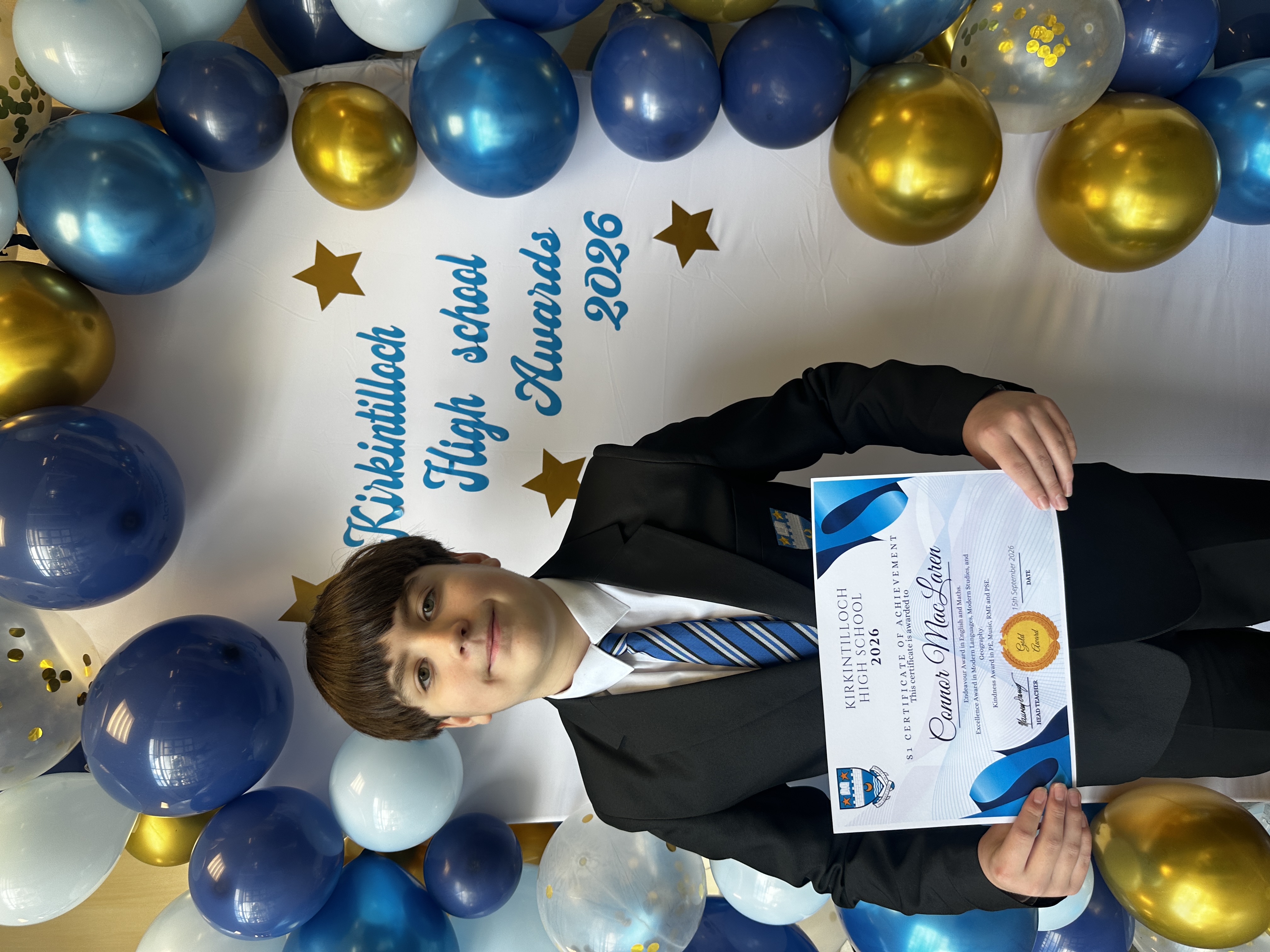 pupil in a blazer holding a certificate