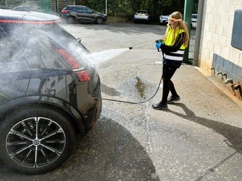 Girl washing a car with a hose