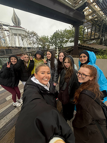 A group of girls taking a selfie next to the rollercoasters